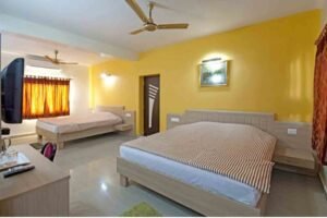 Hotel room with clean double bed, fan and beautiful wall decoration for sundarban package tour from canning