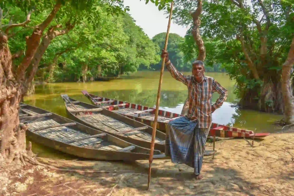 Sundarban fisherman standing near his three boats by riverside